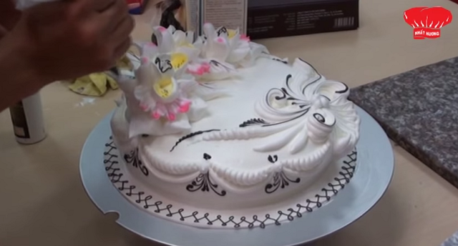 Confeiteiro confeitando bolo, que parece uma obra de arte